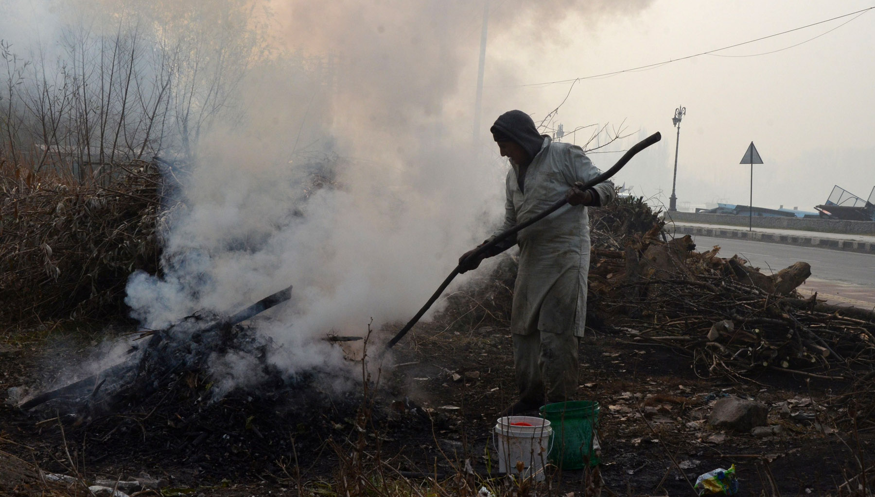 A man burns wood to prepare charcoal which is used by people to keep themselves warm in winters. Photo: Mubashir Khan for Greater Kashmir